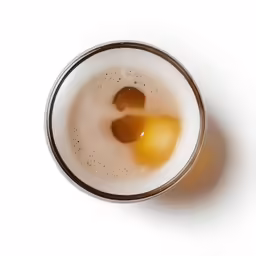 a glass of beer with a small egg in the middle