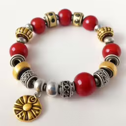 bracelet with a red and gold medallion,the beads are connected with charms and a charm on the bracelet