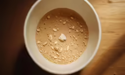 a white cup filled with liquid and a brown base