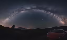 car parked beneath the galactic sky with star trails