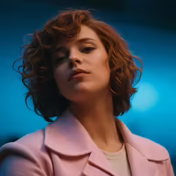 a beautiful young woman in a pink coat staring into the distance