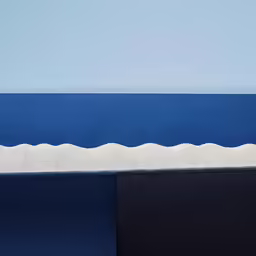 a skateboarder goes down the slope against the blue wall