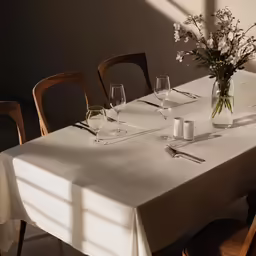 there is a long table with white tables and chairs