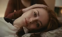a beautiful young woman lying down on top of a bed