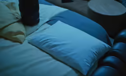a bed with a black lamp and a blue pillow