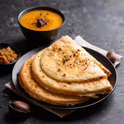 a stack of flat breads next to bowls with garlic