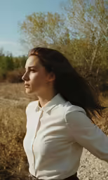 a woman walking in the grass while wearing a tie