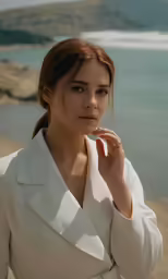 a woman with a coat is standing near the beach