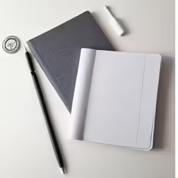 a notepad, pen and envelope next to a paper cutter