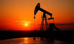 an oil pump and a sunset behind it