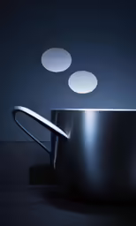 a bowl with silver handles sitting next to a spoon