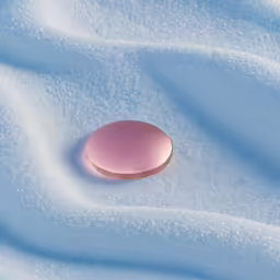 a pink button sitting on the white fabric