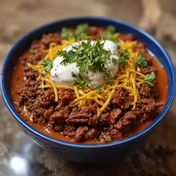 a plate of chili and cheese covered ground beef