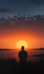 person standing under a colorful sunset on a clear day