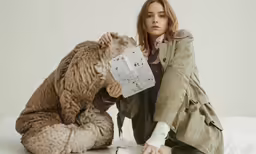 two women wearing large animal costumes, posing on a bed