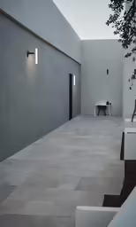a concrete patio with a plant and a stool