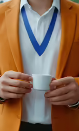 a man in an orange blazer holding a cup