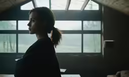 a young girl looks out from the window of an attic dwelling
