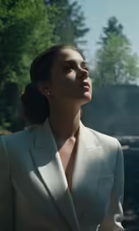 a woman in a suit and earrings looks away from the camera