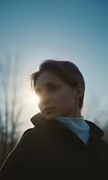 a woman is standing in the sun and staring