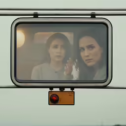 two women on a bus with their hands on the mirror