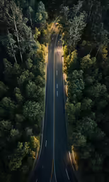 an aerial view of a long road with the lights on