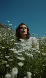 woman sitting in flowers with her head pressed against the side