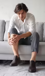 a man sitting on a couch in his white shirt