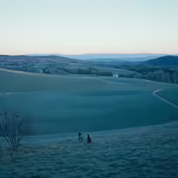 two people walking down a hill on a foggy day