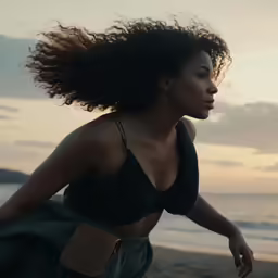 a woman with an afro standing on the beach