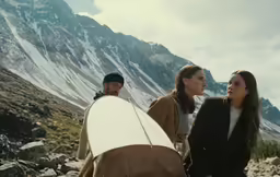 a group of people holding surfboards near some mountains