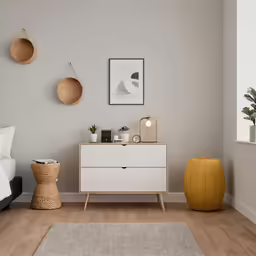 white nightstand and dresser with a plant in the corner