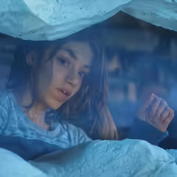 a woman who is laying down under a blanket