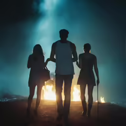 the silhouette of three people standing together in front of a fire