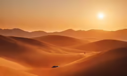 a vehicle driving on the desert during sunset