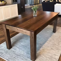 a brown table in a living room with a gray rug