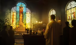 a priest is in front of a stained glass window