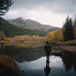 a man with a backpack walks near a pond
