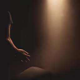 a man reaching out to his left hand in the dark