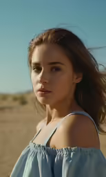 a woman with her hair flying over her shoulders in the sand