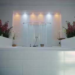 a clean white bathroom with flowers and greenery