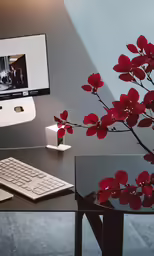 flowers are next to the keyboard on a glass desk