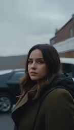 a woman in a brown coat looking up at the camera