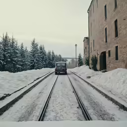a small truck driving down train tracks next to snow covered ground