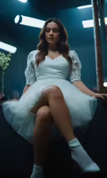 a beautiful woman in white sitting on a counter