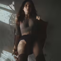 a woman in high heels poses against a wall