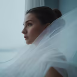 a bride standing near a window wearing a veil