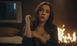 woman with hand up sitting on the floor in front of fire