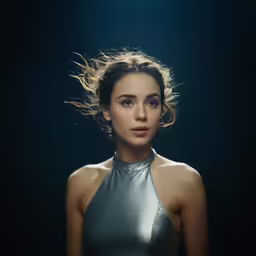 young female in metallic outfit with sun shining behind her