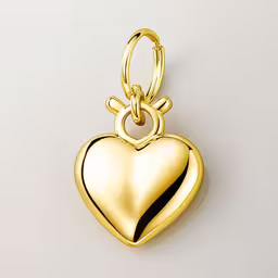 a shiny gold heart pendant hangs on a white background,a gold heart charm that has the shape of a small heart on it